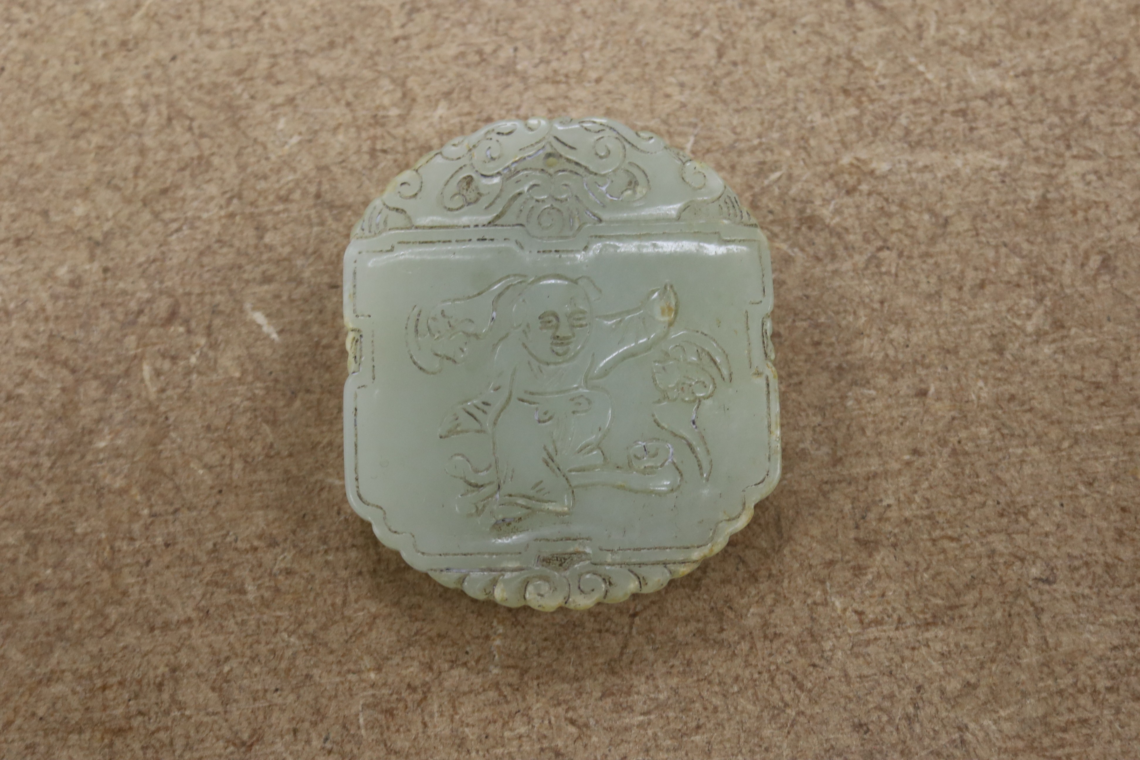 A Chinese pale celadon jade plaque, boy and bats, 5cm wide